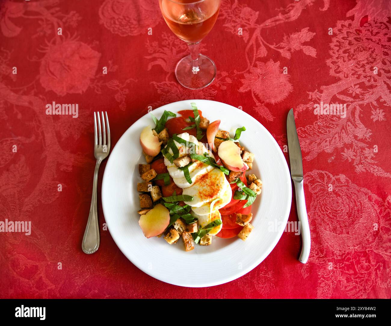 Salade composée, tomates, mozzarella, basilic et pêche avec un verre de rosé Stock Photo