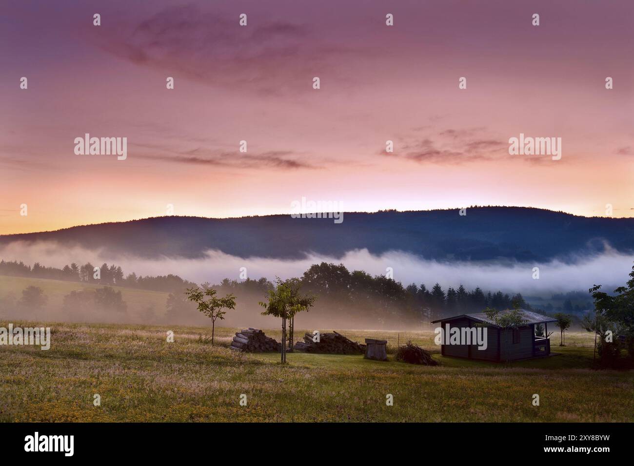 Colorful sunrise on alpine meadows with wooden farm house Stock Photo