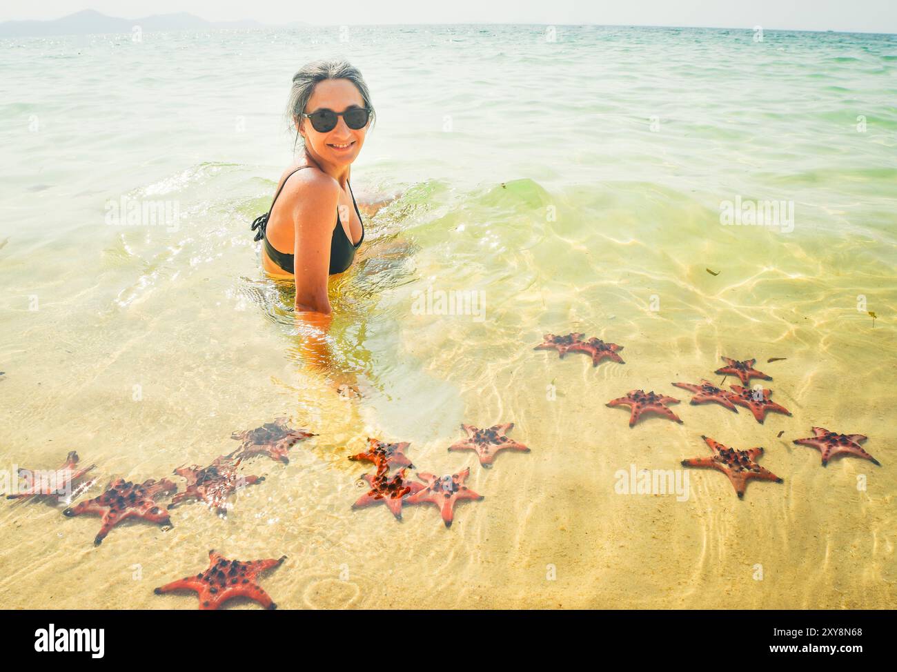 Woman tourist visit star fish beach pick starfish in famous tropical ...