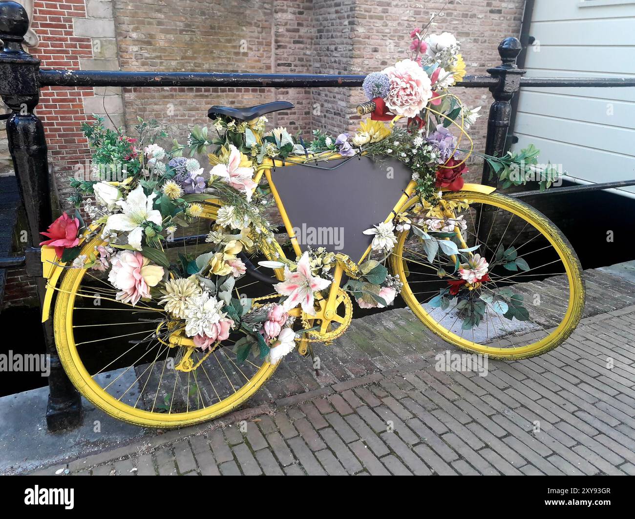 Yellow bicycle decorated with flowers at a canal in Gouda, Netherlands