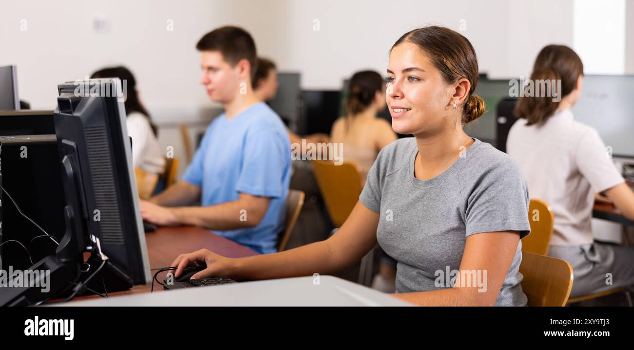 Positive girl using computer in classroom Stock Photo - Alamy