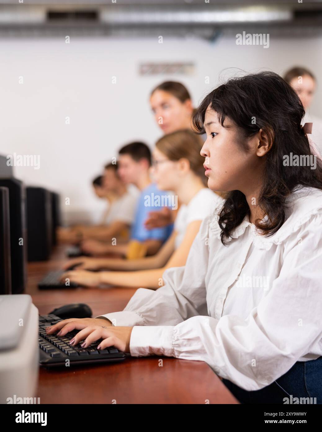 Focused Asian female teenager solving tasks of computer science in the ...