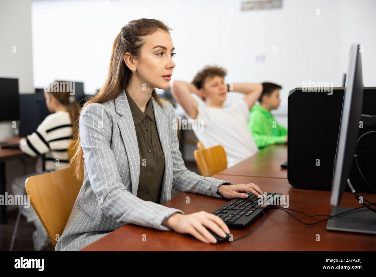 Teacher using computer in classroom Stock Photo - Alamy