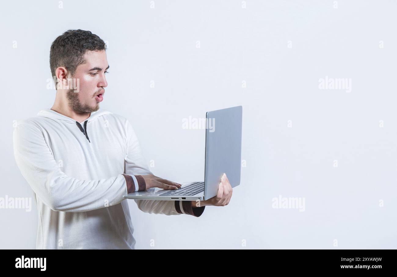 Surprised guy holding and looking at an promotion on laptop screen. Amazed handsome man standing using laptop isolated Stock Photo