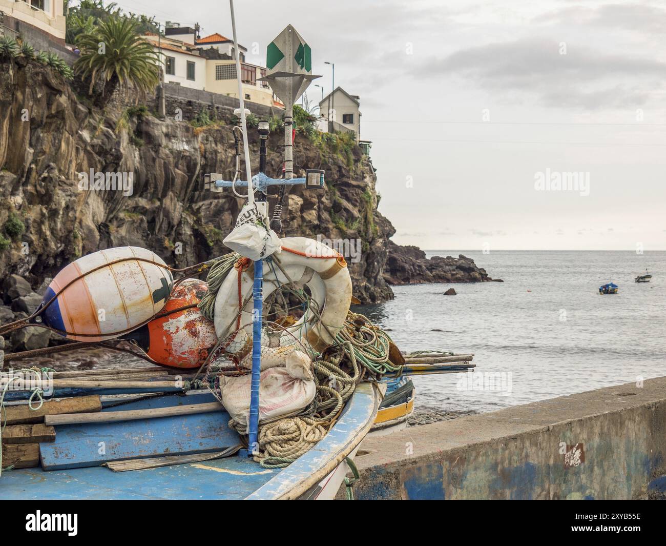 Fishing boats and lifebuoys near a rocky coast under a cloudy sky, Funchal, madeira, portugal Stock Photo