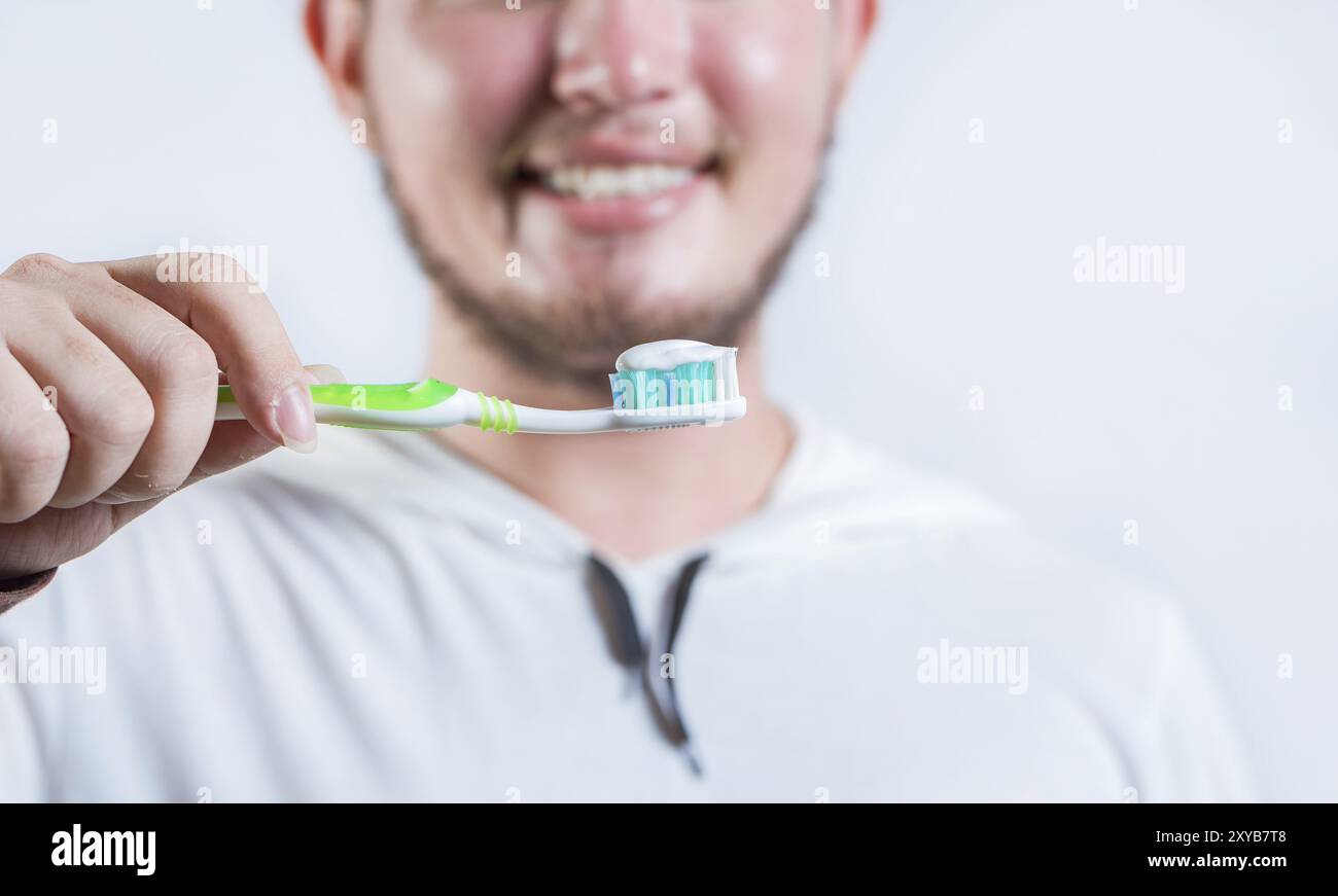 Hand of man showing toothbrush with toothpaste isolated. Close up of hands holding brush with toothpaste Stock Photo