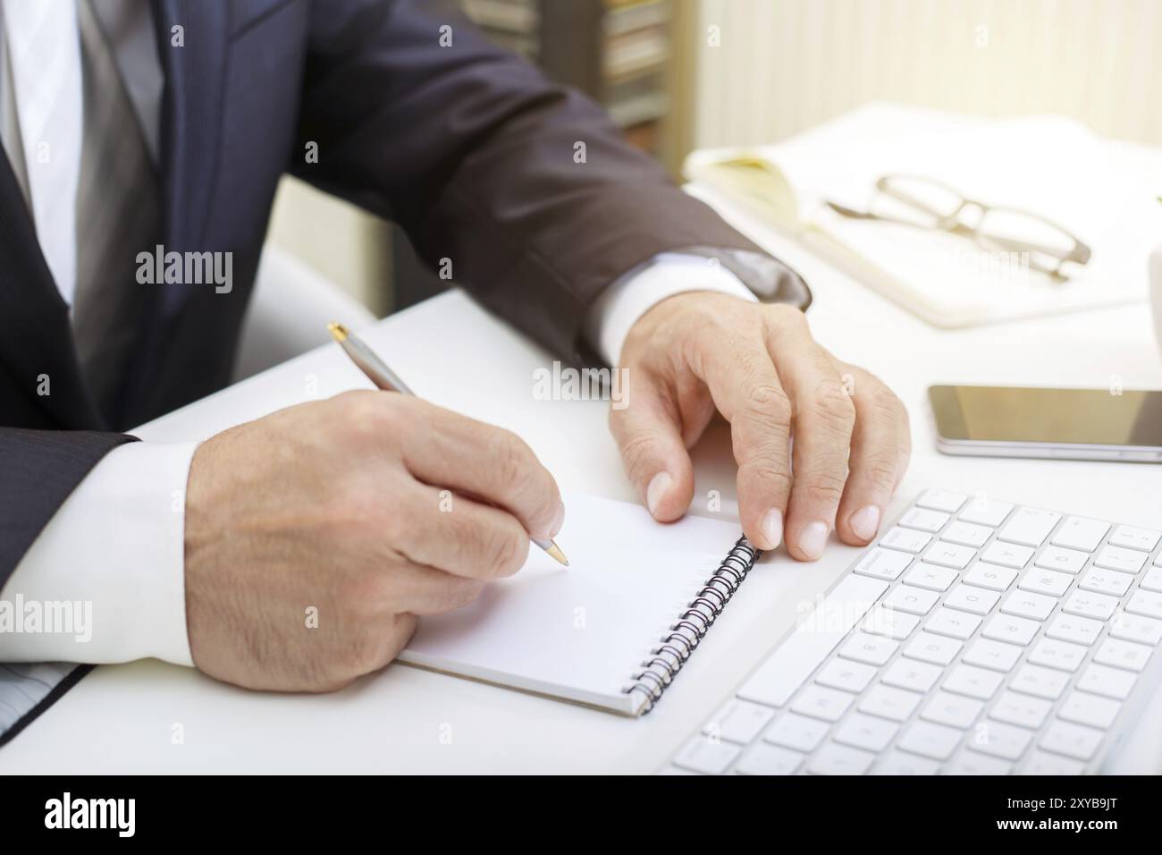 Male hands using modern computer and writing in a notepad business concept close up Stock Photo