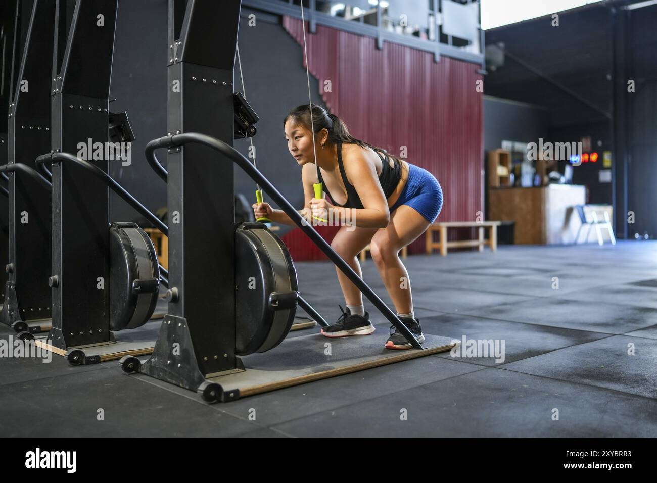 Full length photo of an asian strong woman pulling down weights using ...