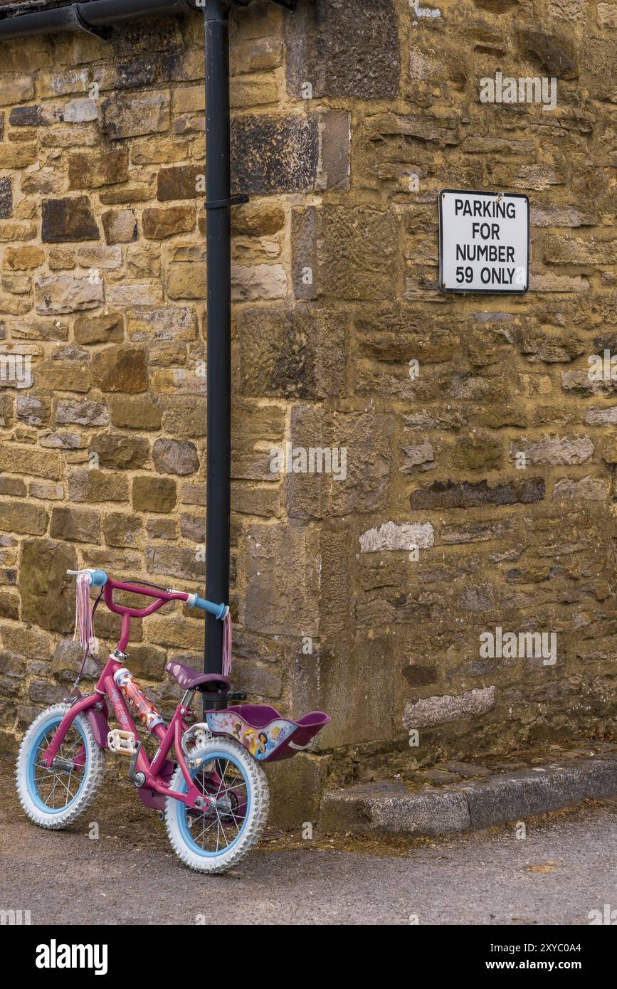 Cononley, North Yorkshire, England, UK, June 04, 2018: A kids bicycle with a sign Parking for number 59 only at the wall of a house Stock Photo