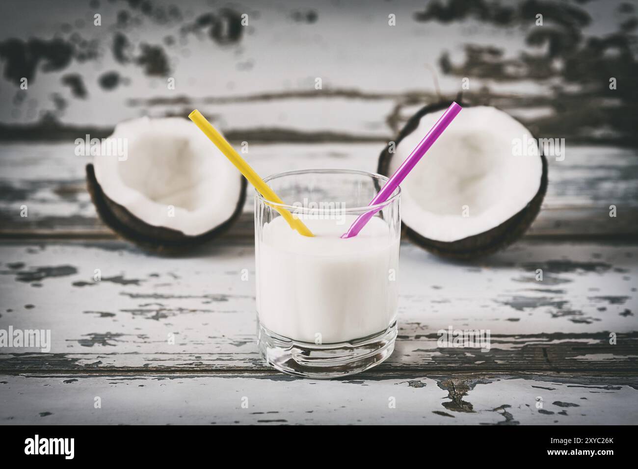 Coconut milk in a glass with two straws over a wooden background Stock Photo