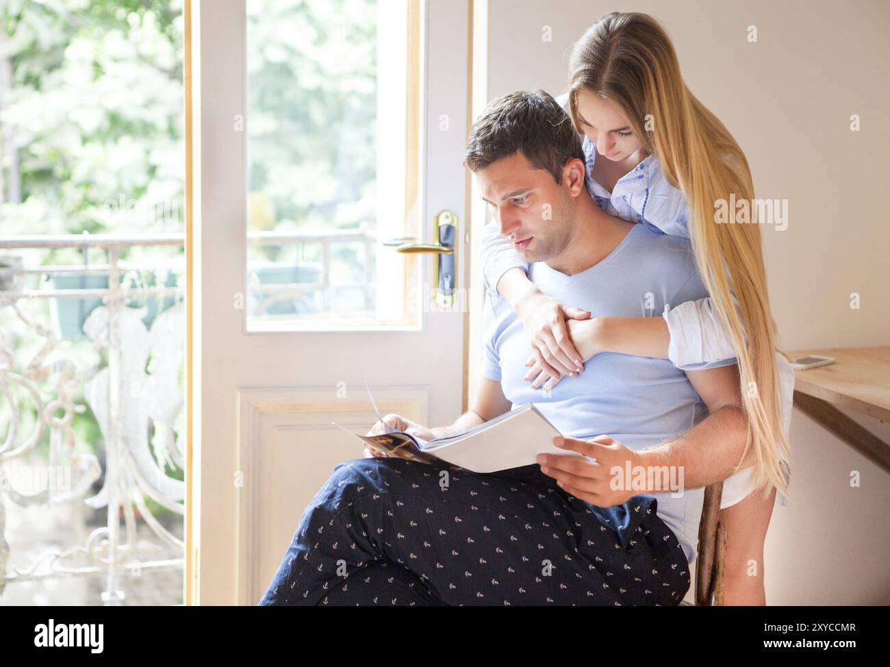 Happy couple reading magazine together at home Stock Photo