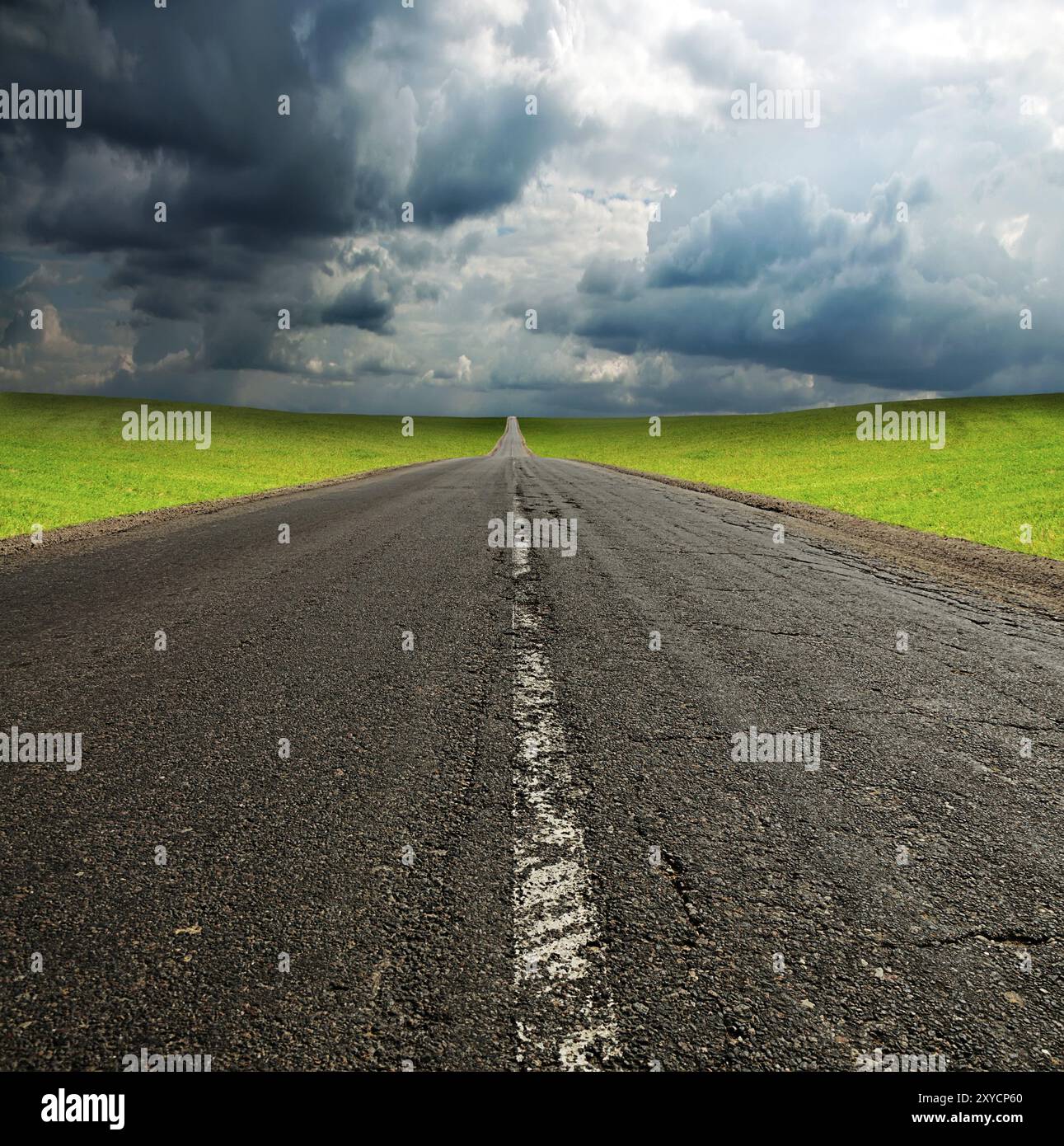 Old broken asphault road in green field over blue cloudy sky Stock Photo