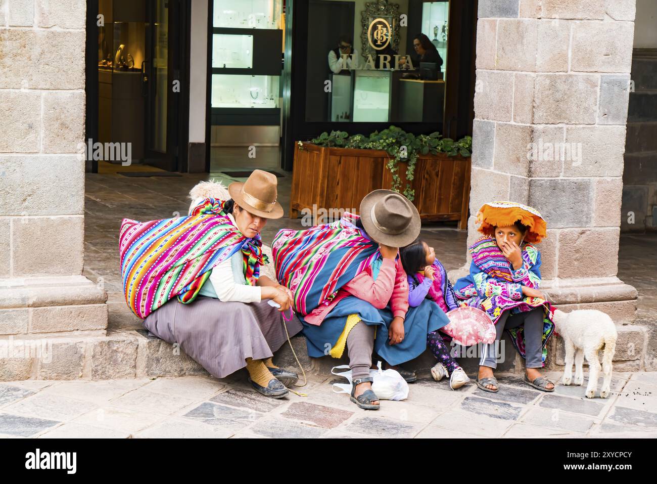 CUSCO, PERU, JANUARY 26, 2016 : Unidentified Peruvian people wearing colorful traditional clothing and hat with their animal sitting in front of a sho Stock Photo