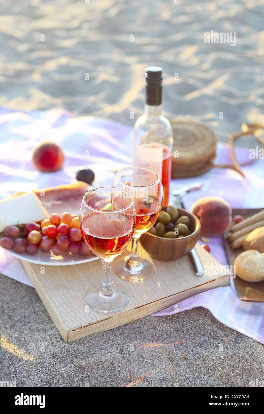 Picnic outdoor with rose wine fruits meat and cheese. Sunset Stock Photo