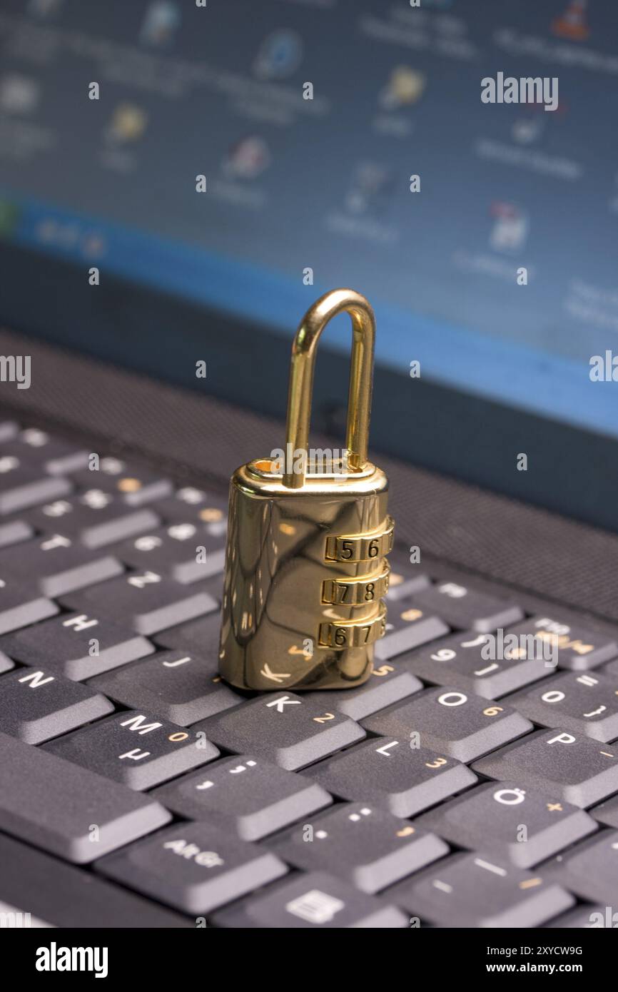 A golden padlock on a black notebook keyboard Stock Photo