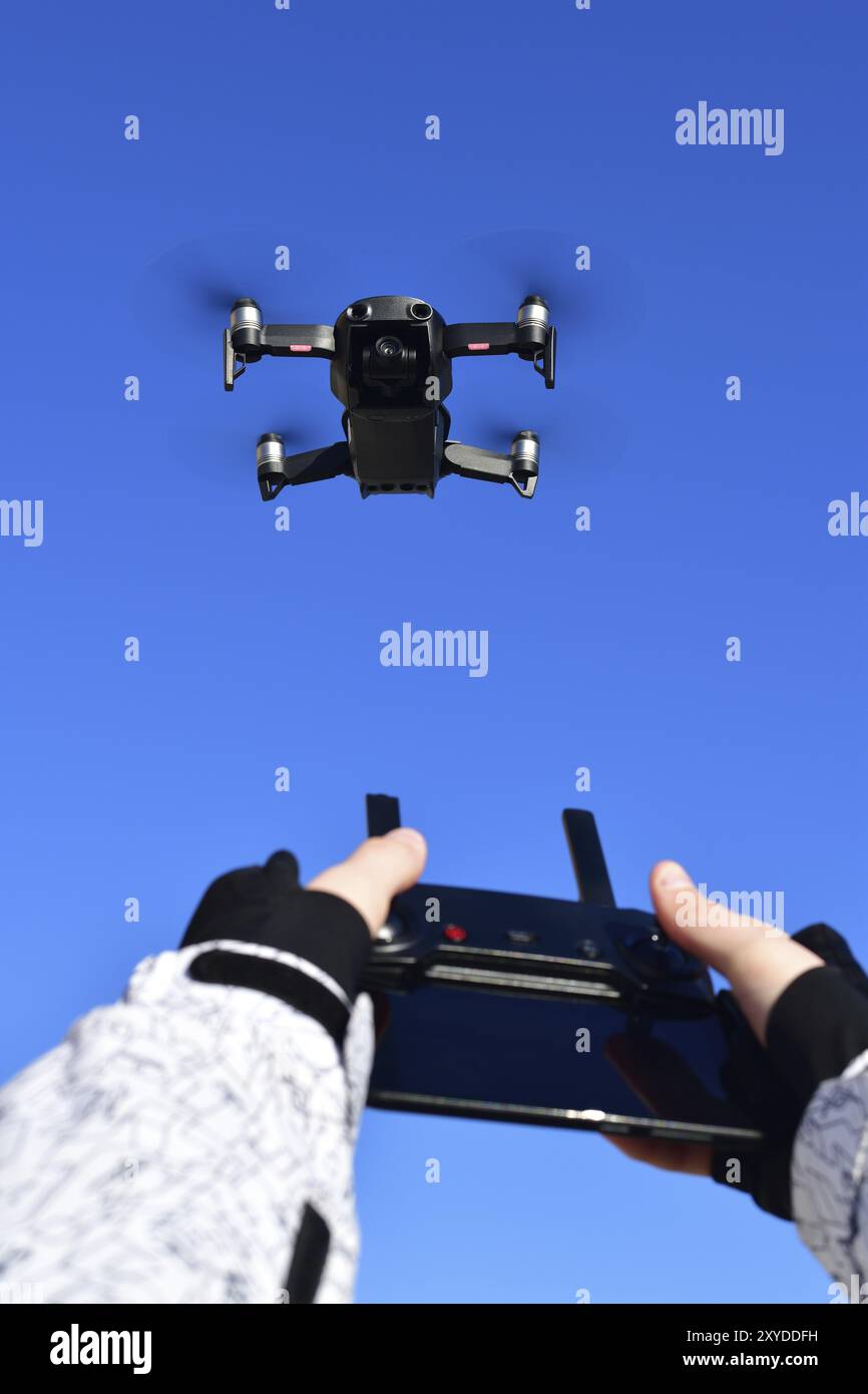 Quadrocopter flies in the sky and hands with a control panel Stock Photo