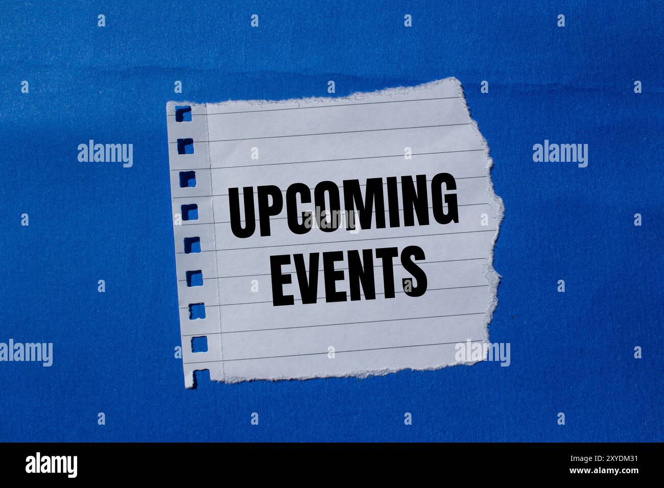 Upcoming events message written on ripped torn paper piece with blue ...