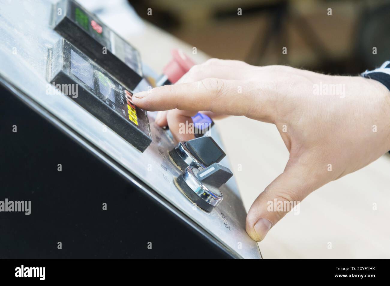 A close-up of the operator the man presses the button on the control panel with the control devices on the furniture production. The man's hand presse Stock Photo