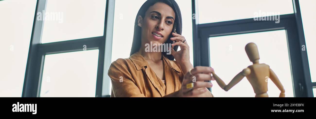 A Middle Eastern woman in a corporate setting talks on the phone while working. Stock Photo
