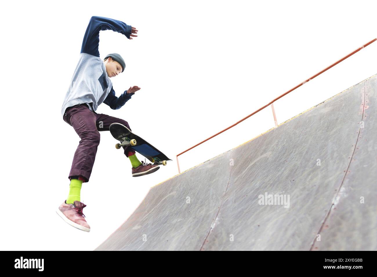 The teenager skateboarder in the cap does a trick with a jump on the ...