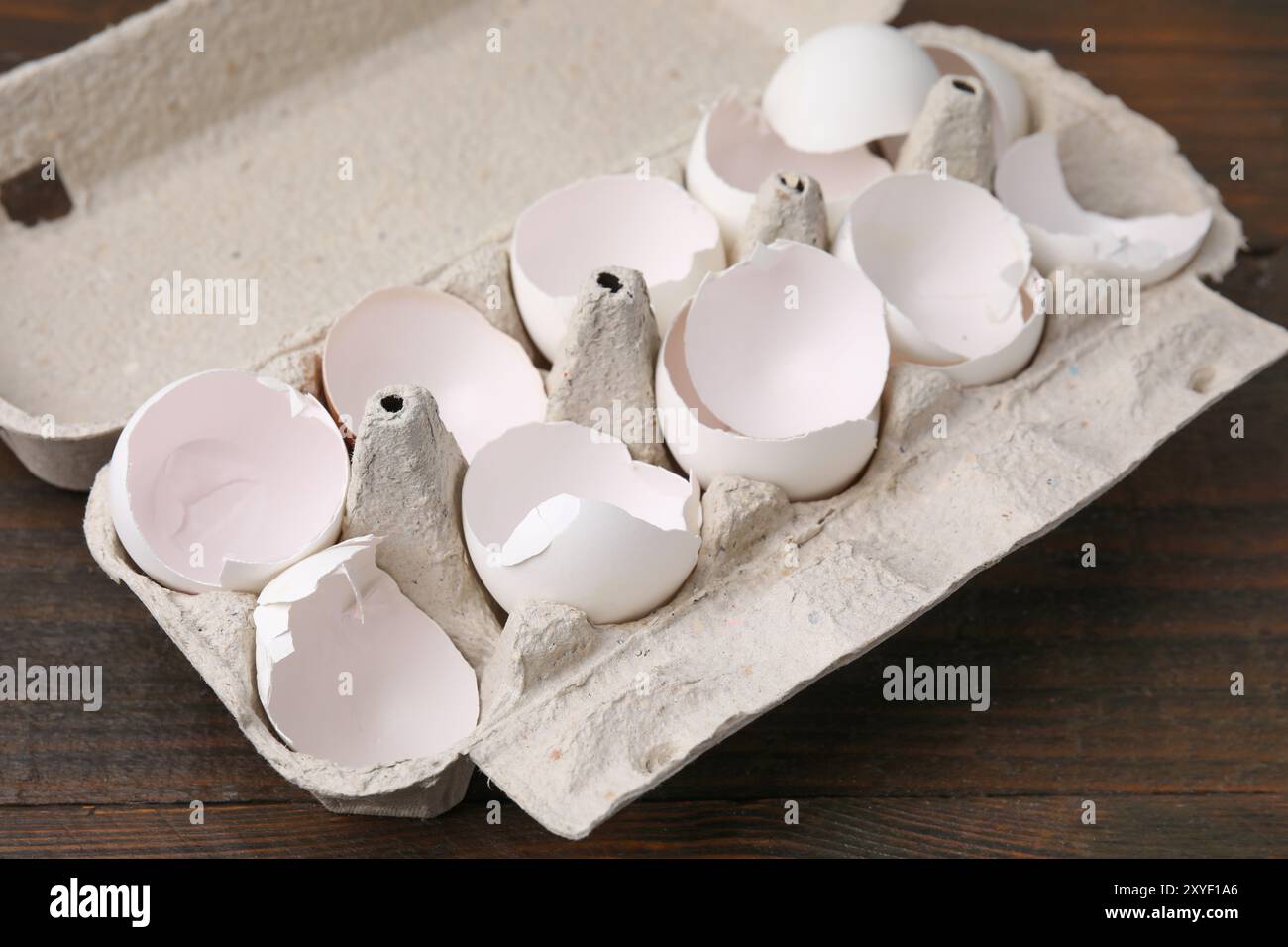 Broken eggshells in carton on wooden table, closeup Stock Photo