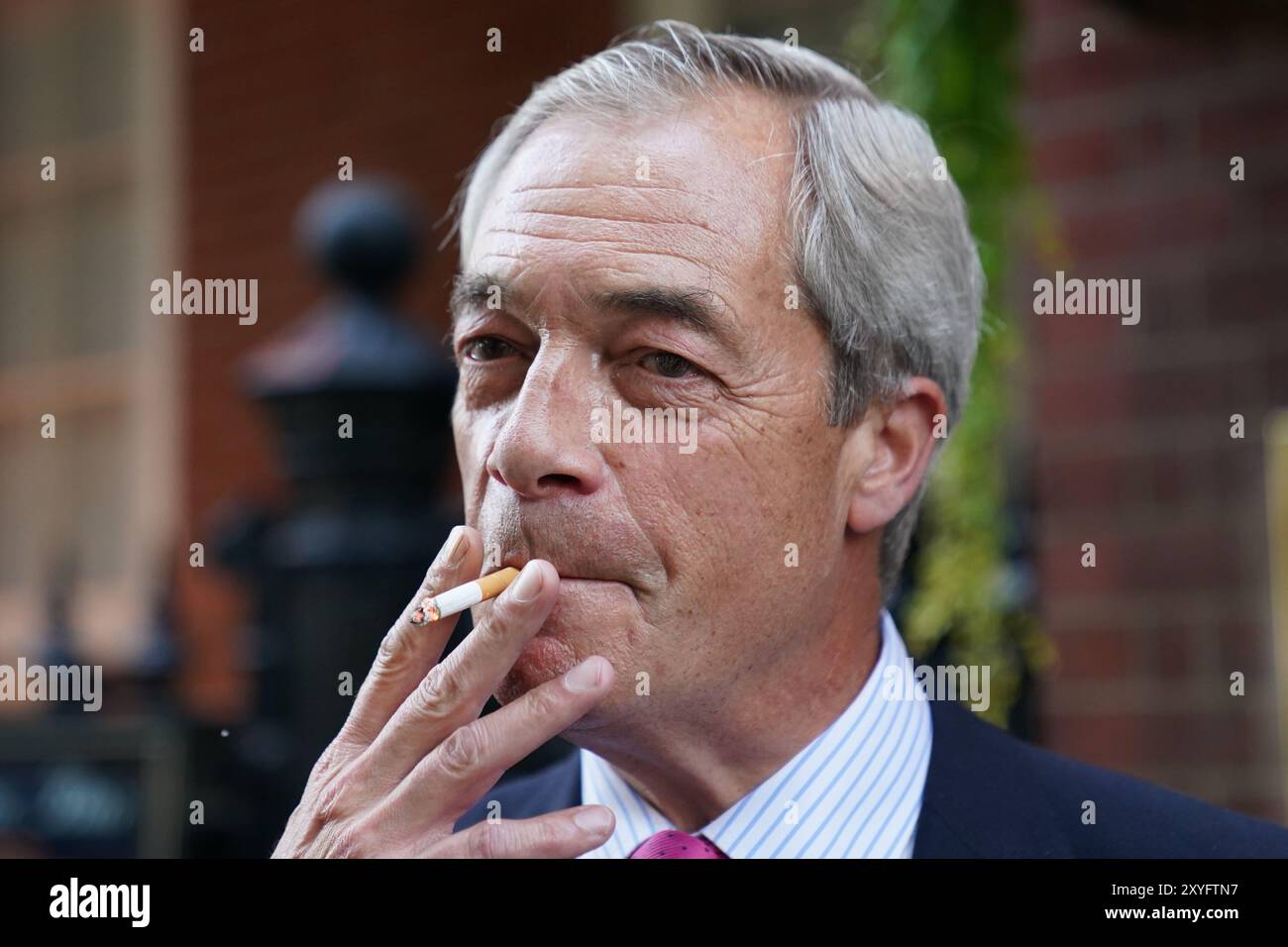Reform UK leader Nigel Farage smoking outside the Westminster Arms pub in  Westminster, London. Sir Keir Starmer has said the Government will 