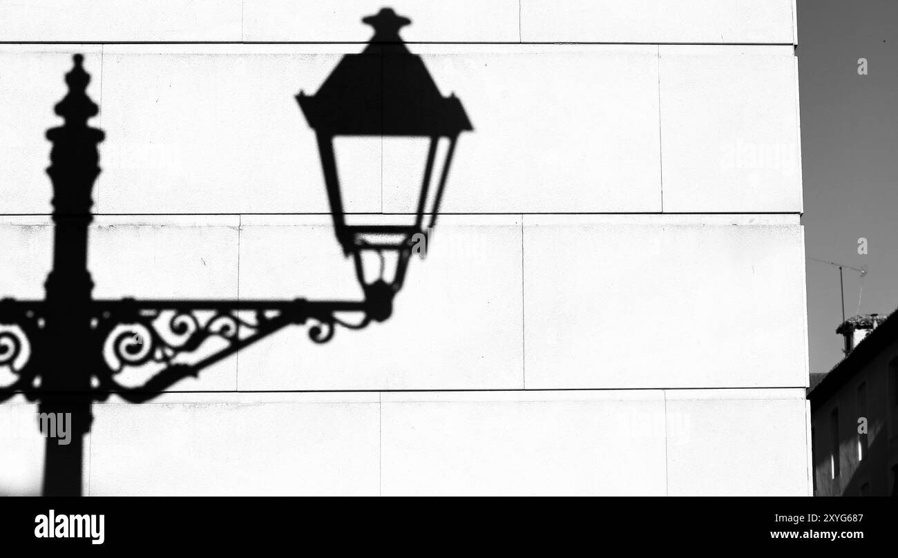 Vintage lamppost shadow on white stone wall of building in Madrid, Spain Stock Photo