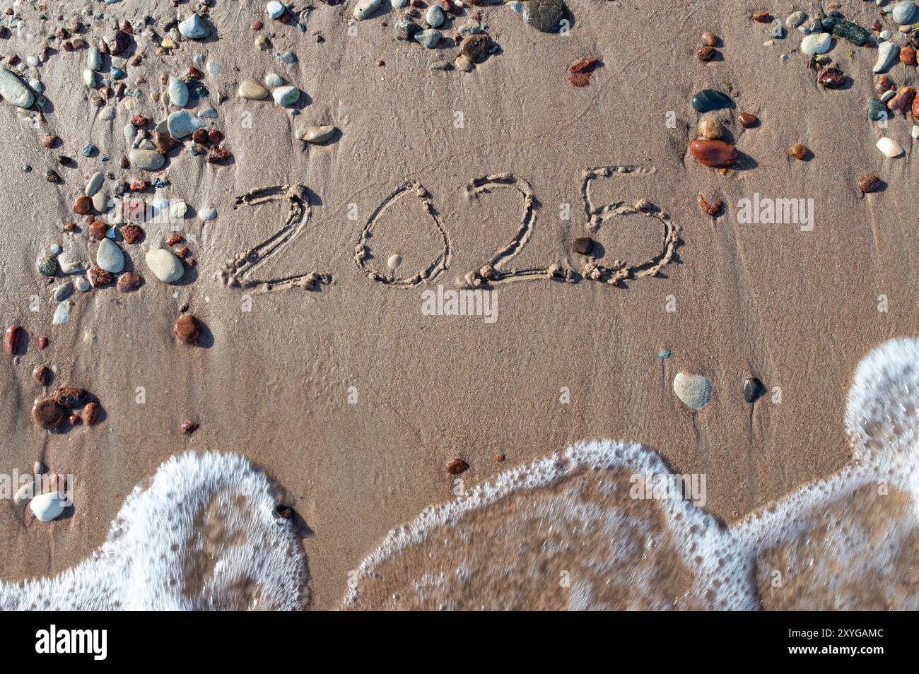 Message Year 2024 replaced by 2025 text written on beach sand background. Good bye 2024 hello to 2025 happy New Year coming concept. top view. Estonia Stock Photo