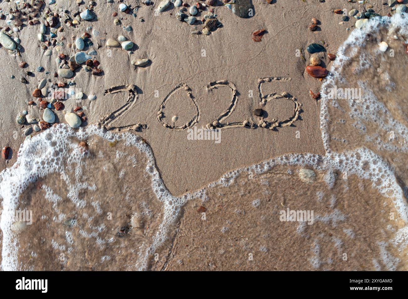 Message Year 2024 replaced by 2025 text written on beach sand background. Good bye 2024 hello to 2025 happy New Year coming concept. top view. Estonia Stock Photo