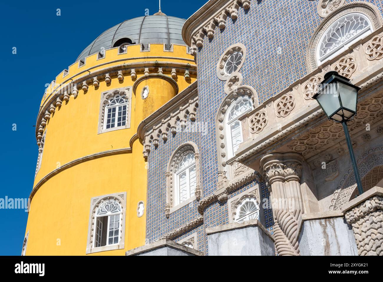 Pena Palace Architecture Sintra Portugal // SINTRA, Portugal — The vibrant and eclectic exterior architecture of Pena Palace, showcasing its blend of Romanticist, Moorish, and Neo-Manueline styles. The palace's colorful facades, ornate details, and whimsical elements epitomize 19th-century Romantic architecture and King Ferdinand II's vision of a fairytale castle. Stock Photo