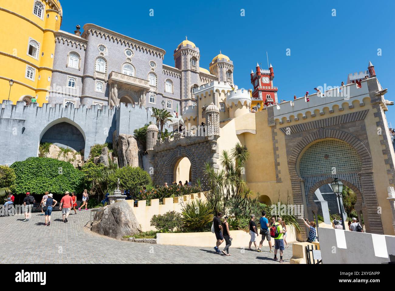 Pena Palace Exterior Architecture Sintra Portugal // SINTRA, Portugal — The vibrant and eclectic exterior architecture of Pena Palace, showcasing its blend of Romanticist, Moorish, and Neo-Manueline styles. The palace's colorful facades, ornate details, and whimsical elements epitomize 19th-century Romantic architecture and King Ferdinand II's vision of a fairytale castle. Stock Photo