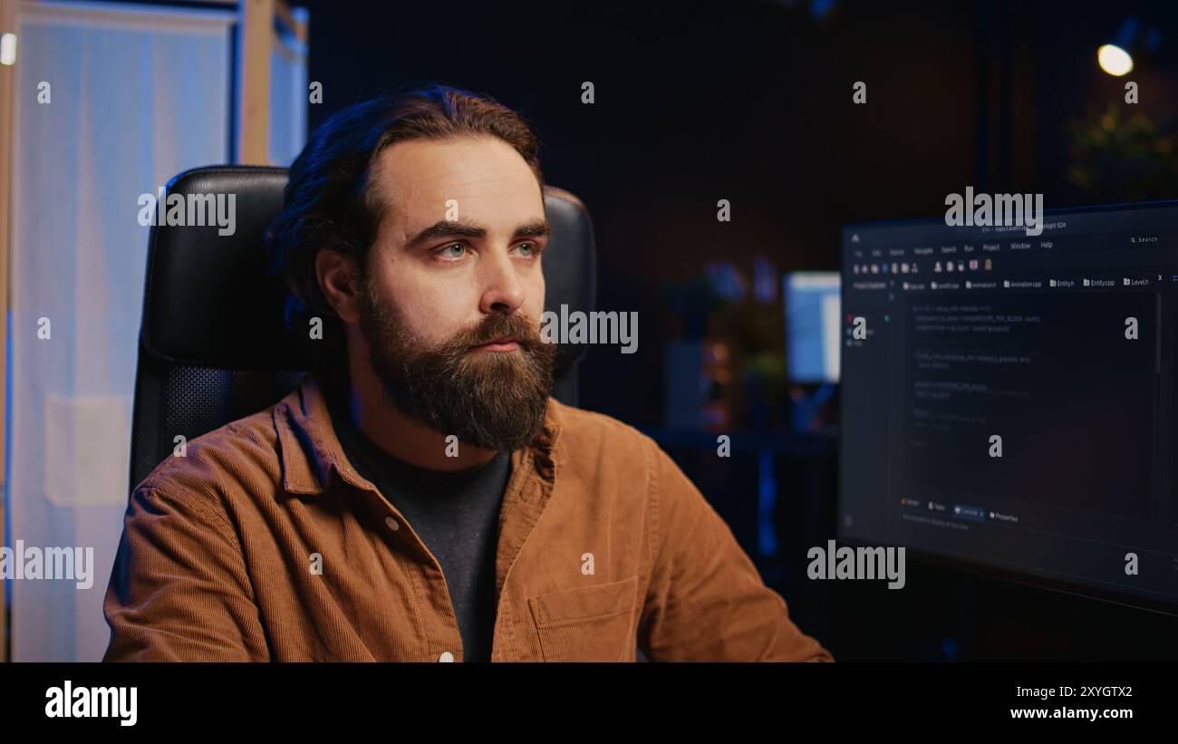 Developer overthinking solutions while doing programming during remote job shift in home office while drinking coffee. IT admin enjoying hot beverage working on PC early in the morning, camera B Stock Photo
