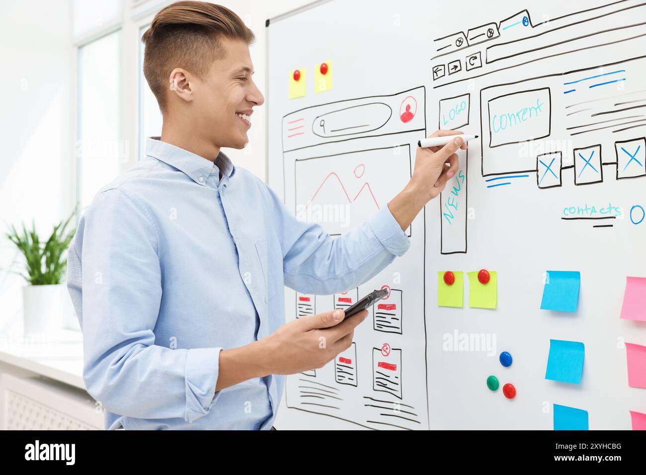 Developing UI design. Man drawing website wireframe on whiteboard indoors Stock Photo