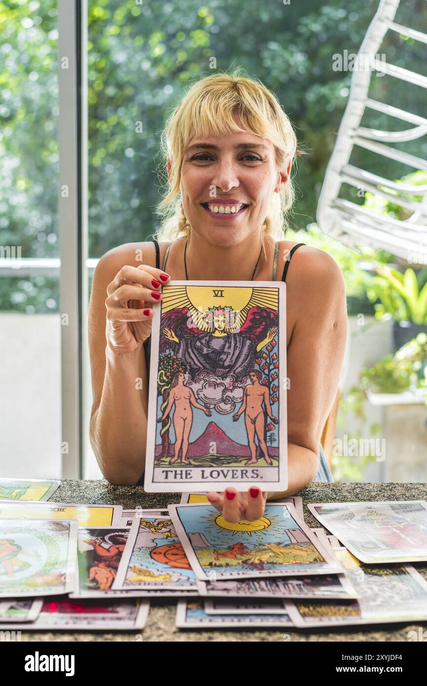 Tarotreader Smiling tarot reader showcasing the giant Tarot card The Lovers while ...