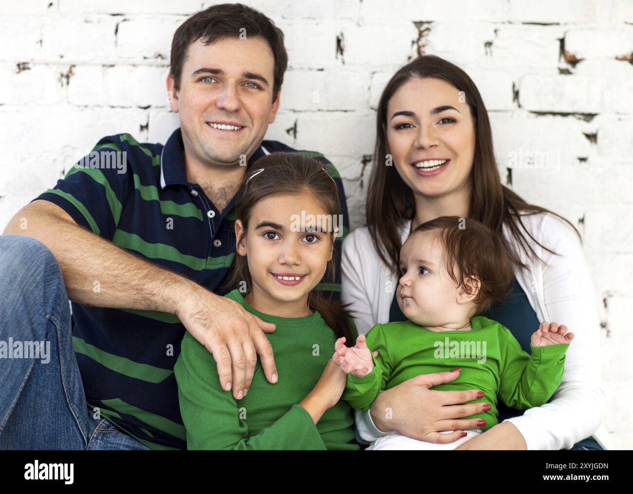 Portrait of a happy smiling family near white brick wall Stock Photo ...