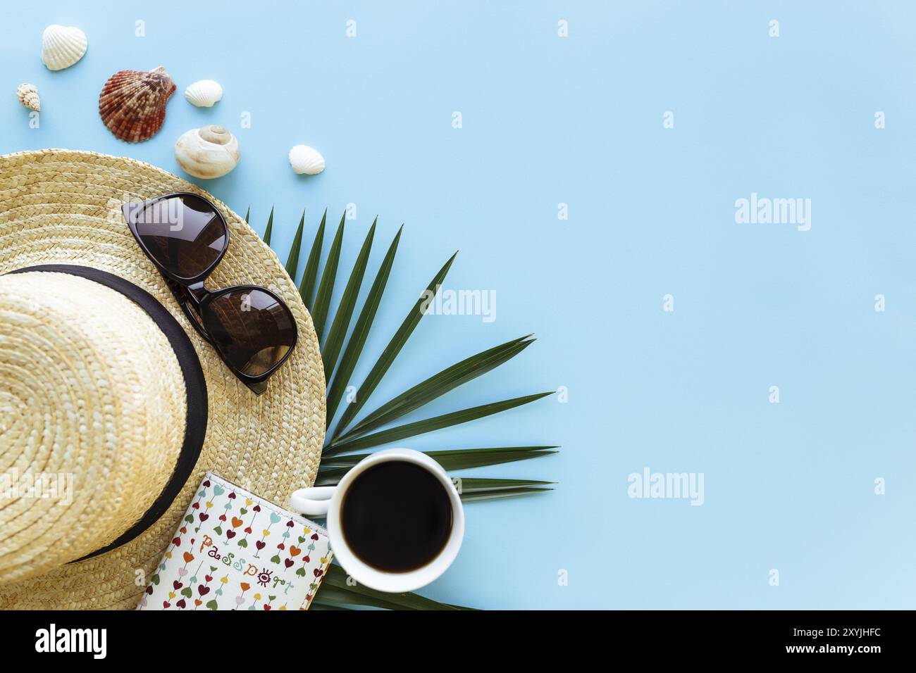 Travel, vacation concept. Hat with sea shells, palm leaf, passport, eyeglasses and cup of coffee on blue background. Stock Photo