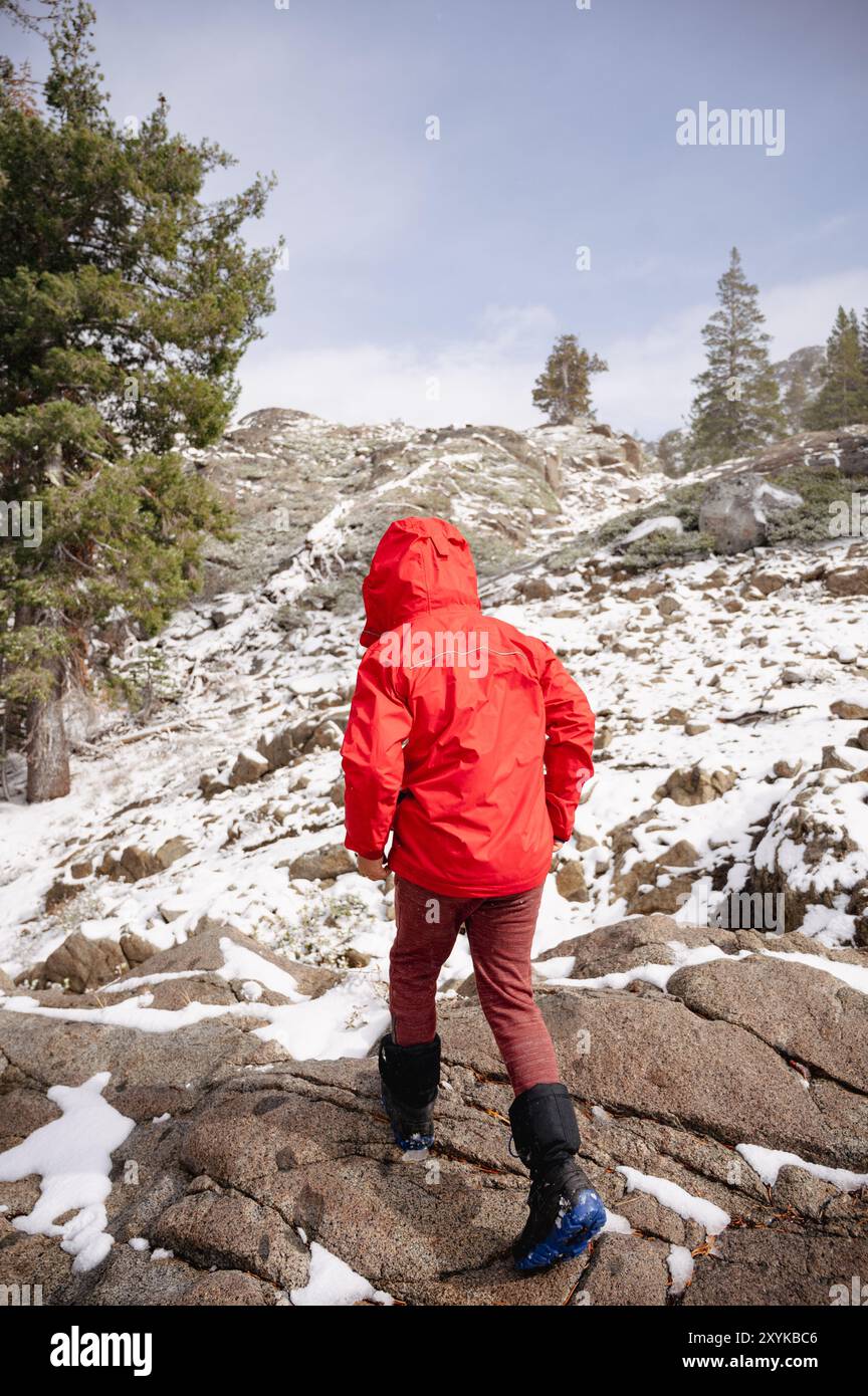 Boy in red jacket hikes along granite trail near Lake Tahoe Stock Photo