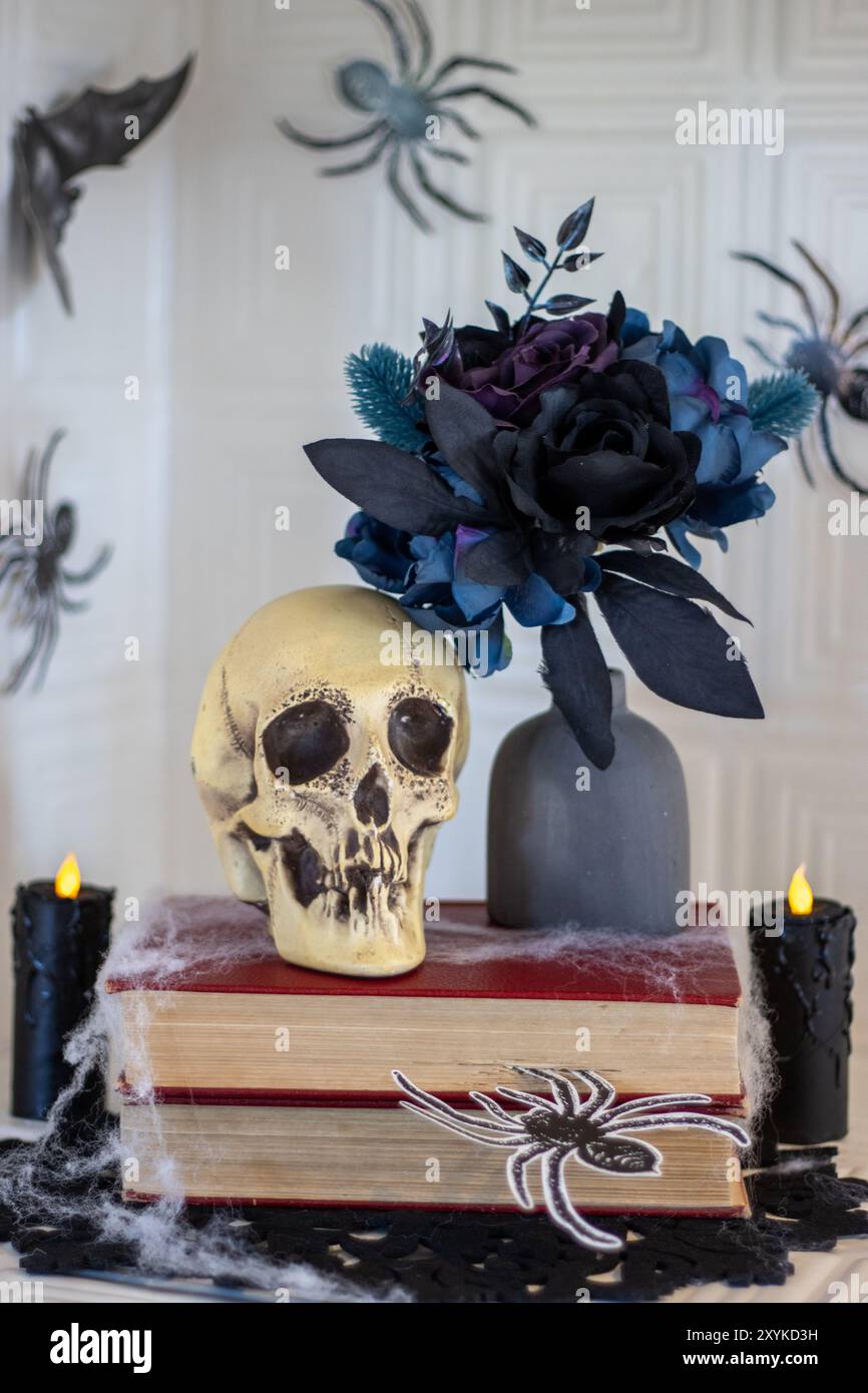 Skull and dark flowers on books, surrounded by spiders and candles Stock Photo