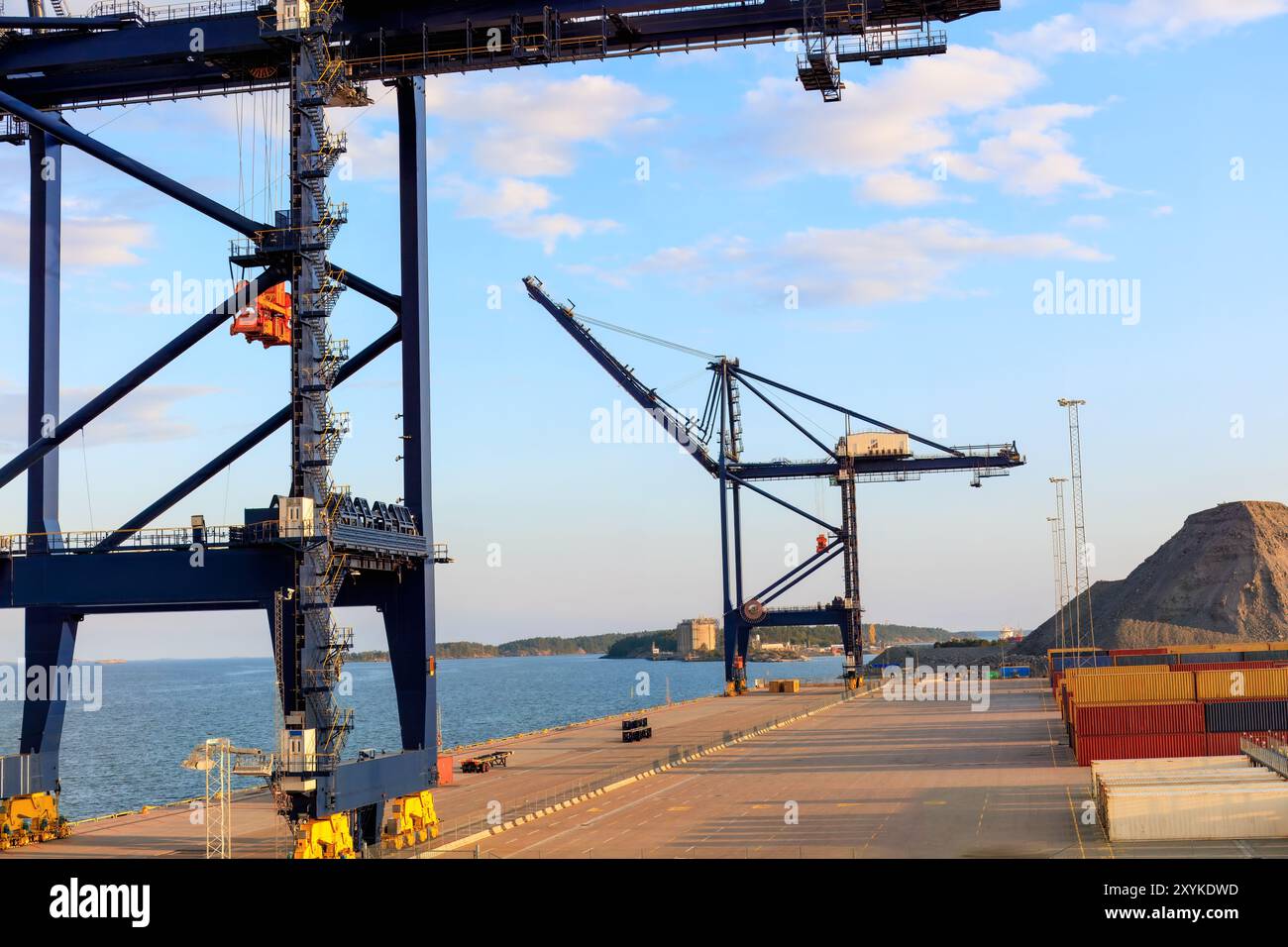 Container cranes at a harbor during sunset. Ideal image for themes related to global trade, industrial operations, and shipping logistics. Stock Photo
