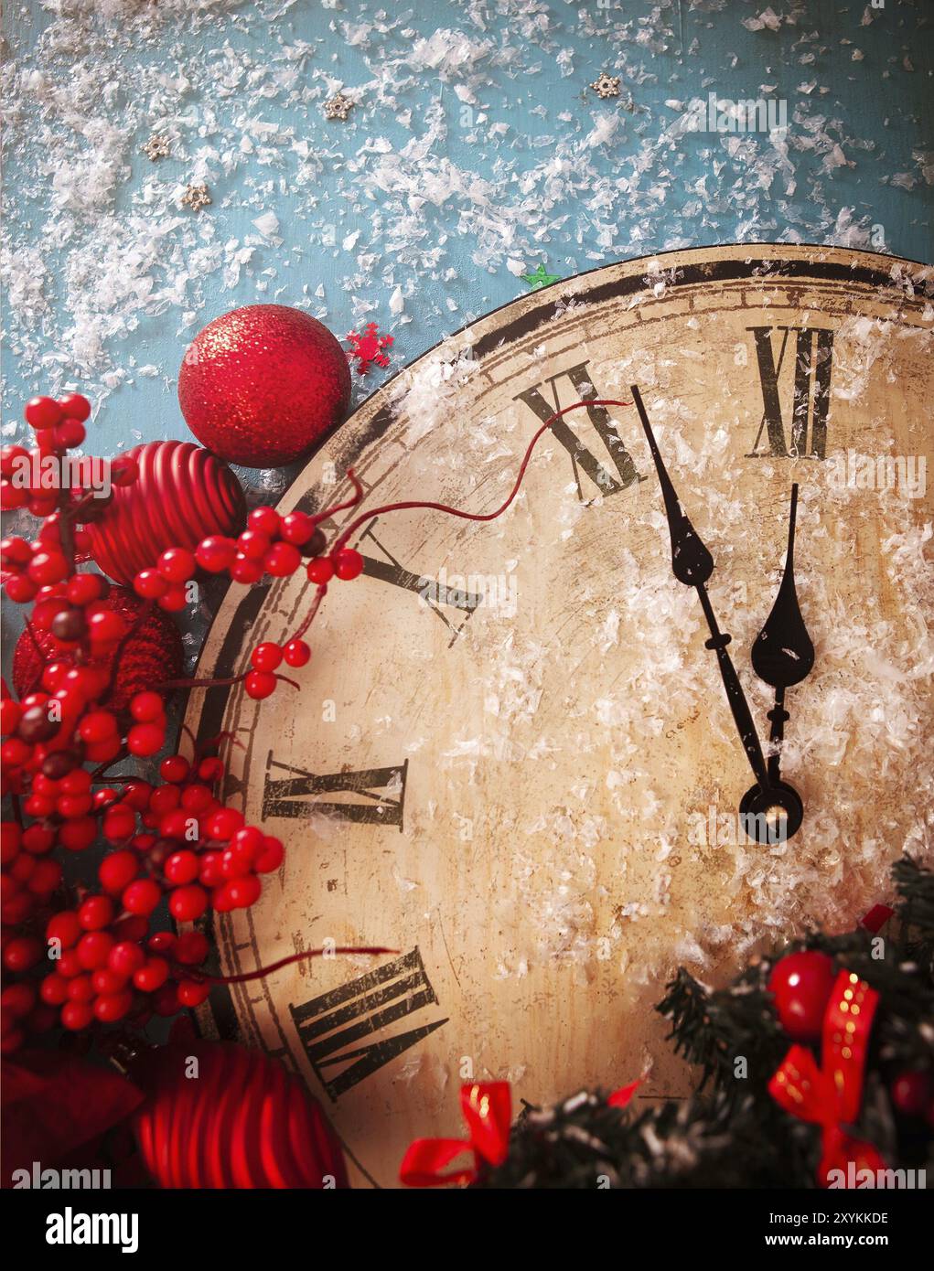 From above of retro wooden clock showing almost midnight placed with various red decorative elements on blue table with white snowflakes Stock Photo