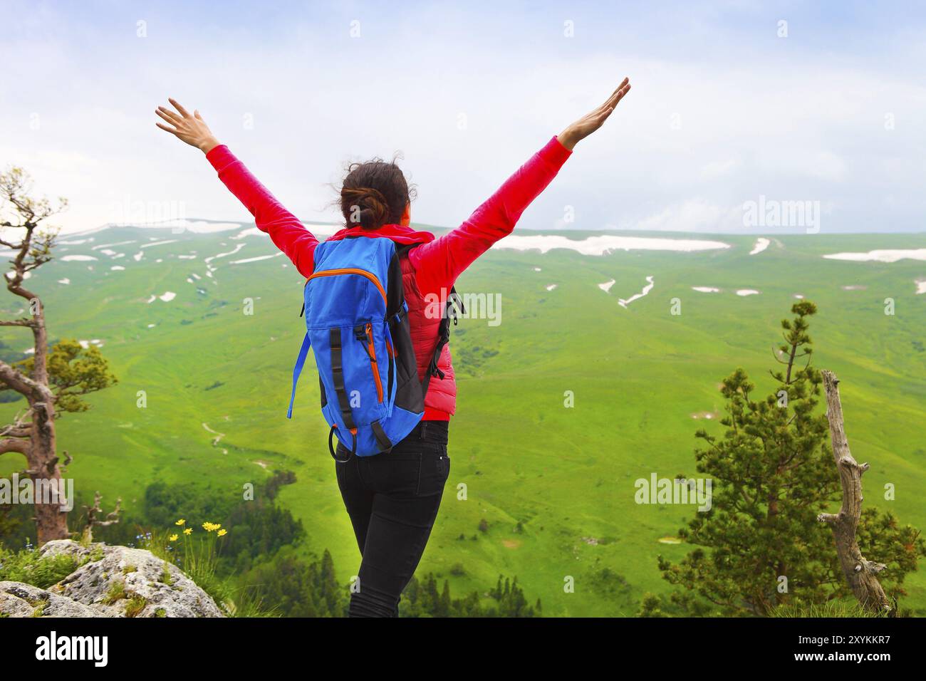Hiker woman with backpack relaxing on top of a mountain and enjoying ...
