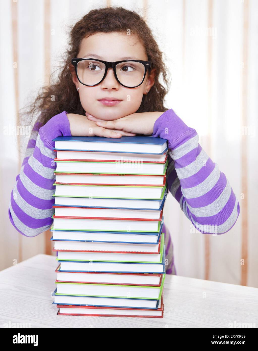 Little brunette girl with pile of books Stock Photo - Alamy