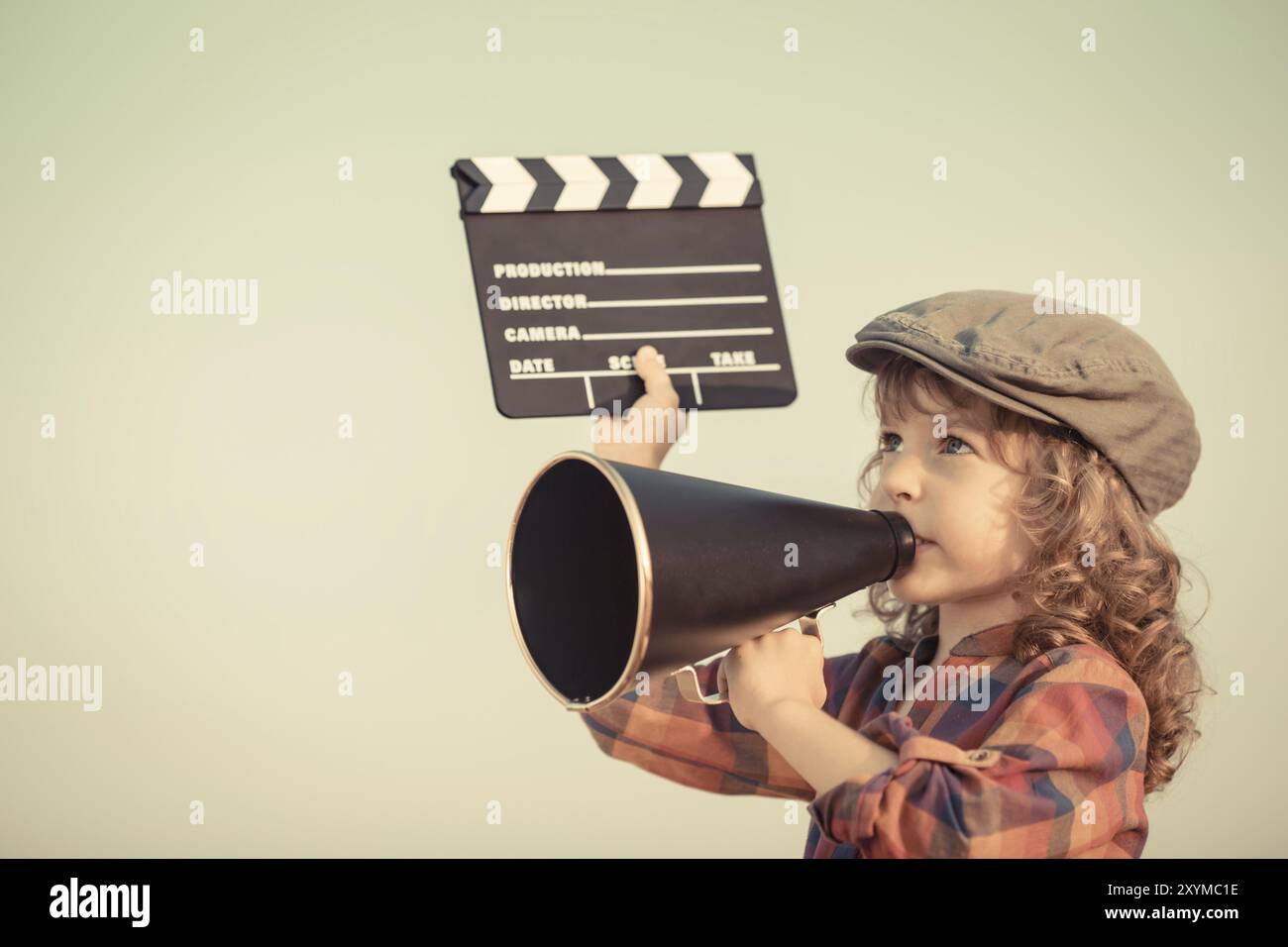 Kid holding clapper board and shouting through vintage megaphone. Cinema concept. Retro style Stock Photo