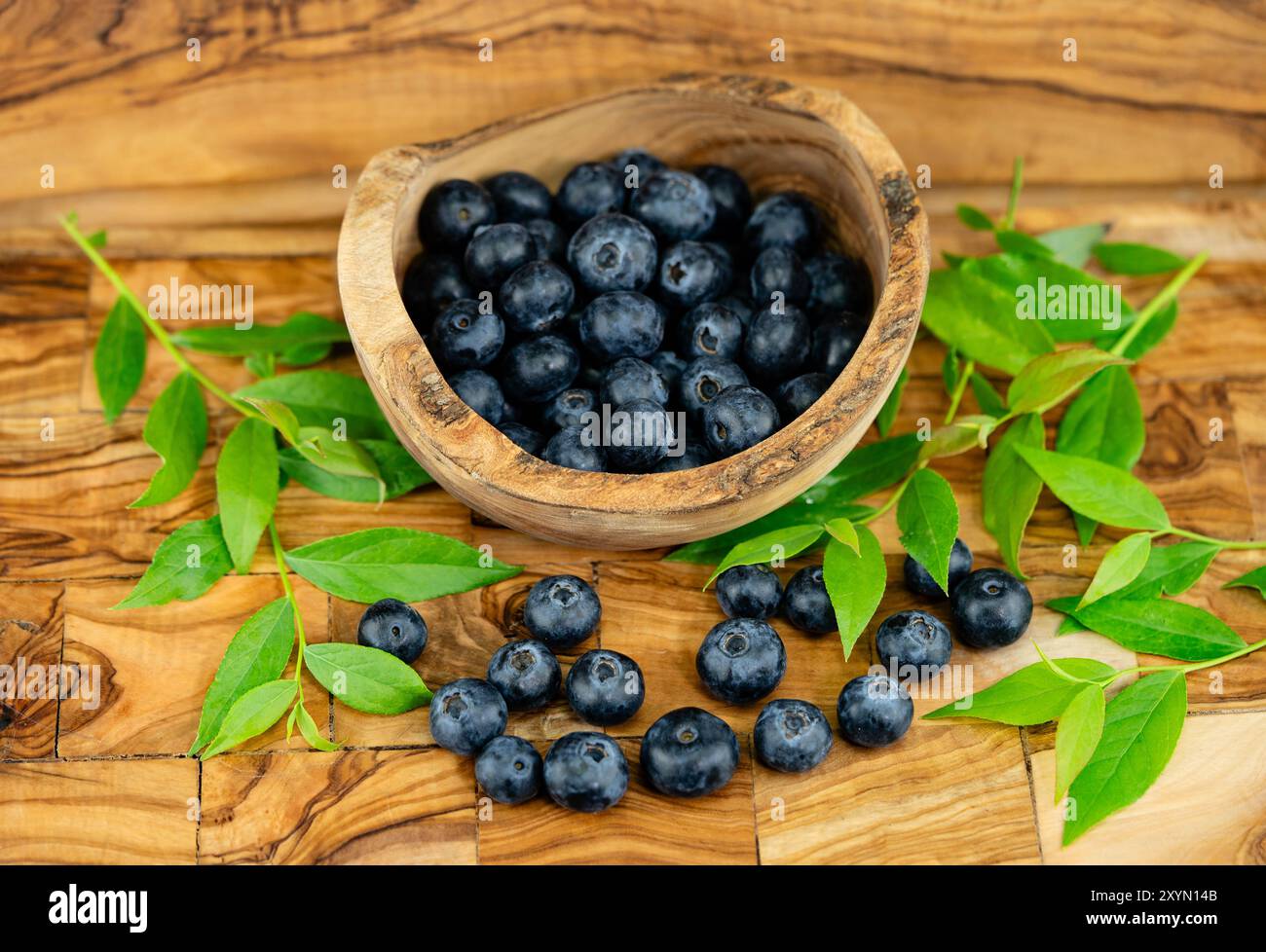 dwarf bilberry, blueberry, huckleberry, low billberry (Vaccinium myrtillus), blueberries in a wooden bowl with twigs Stock Photo