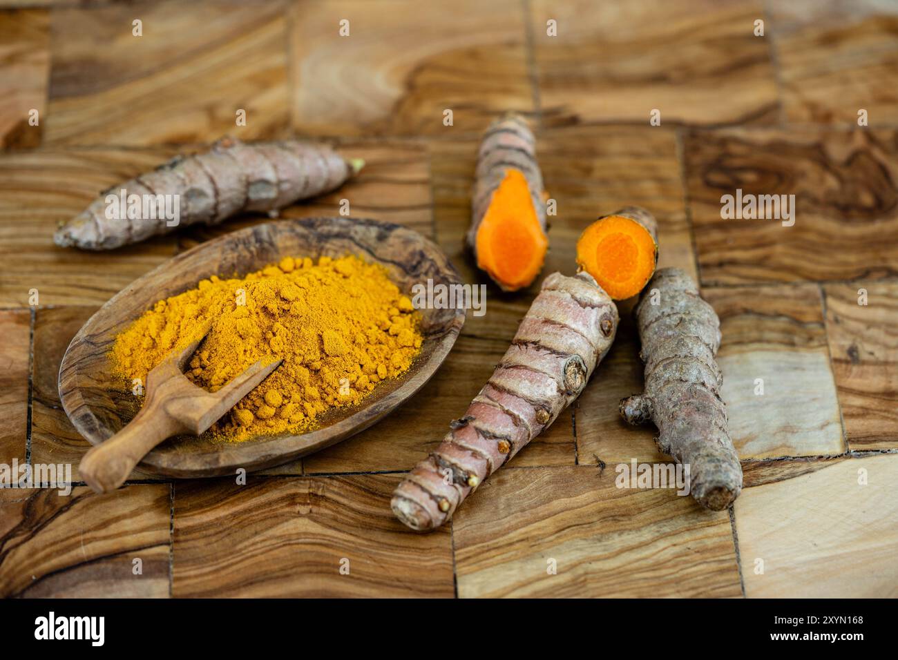 turmeric (Curcuma longa), Rhizomes, fresh and cut, as well as dried and ground on a plate with a wooden scoop Stock Photo