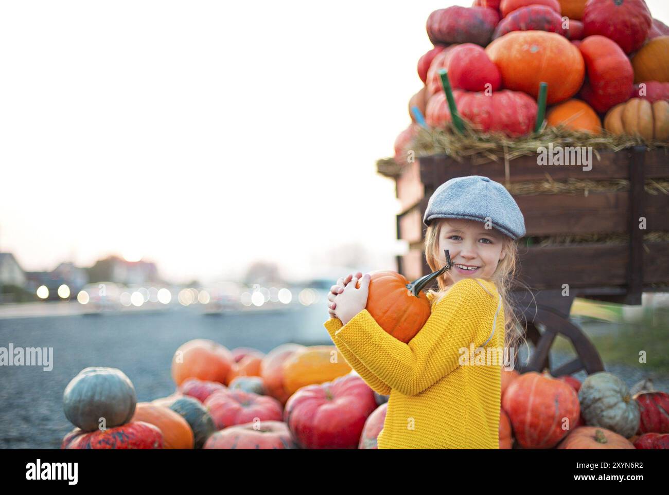 Happy little girl at the autumn pumpkin patch background. Having fun ...