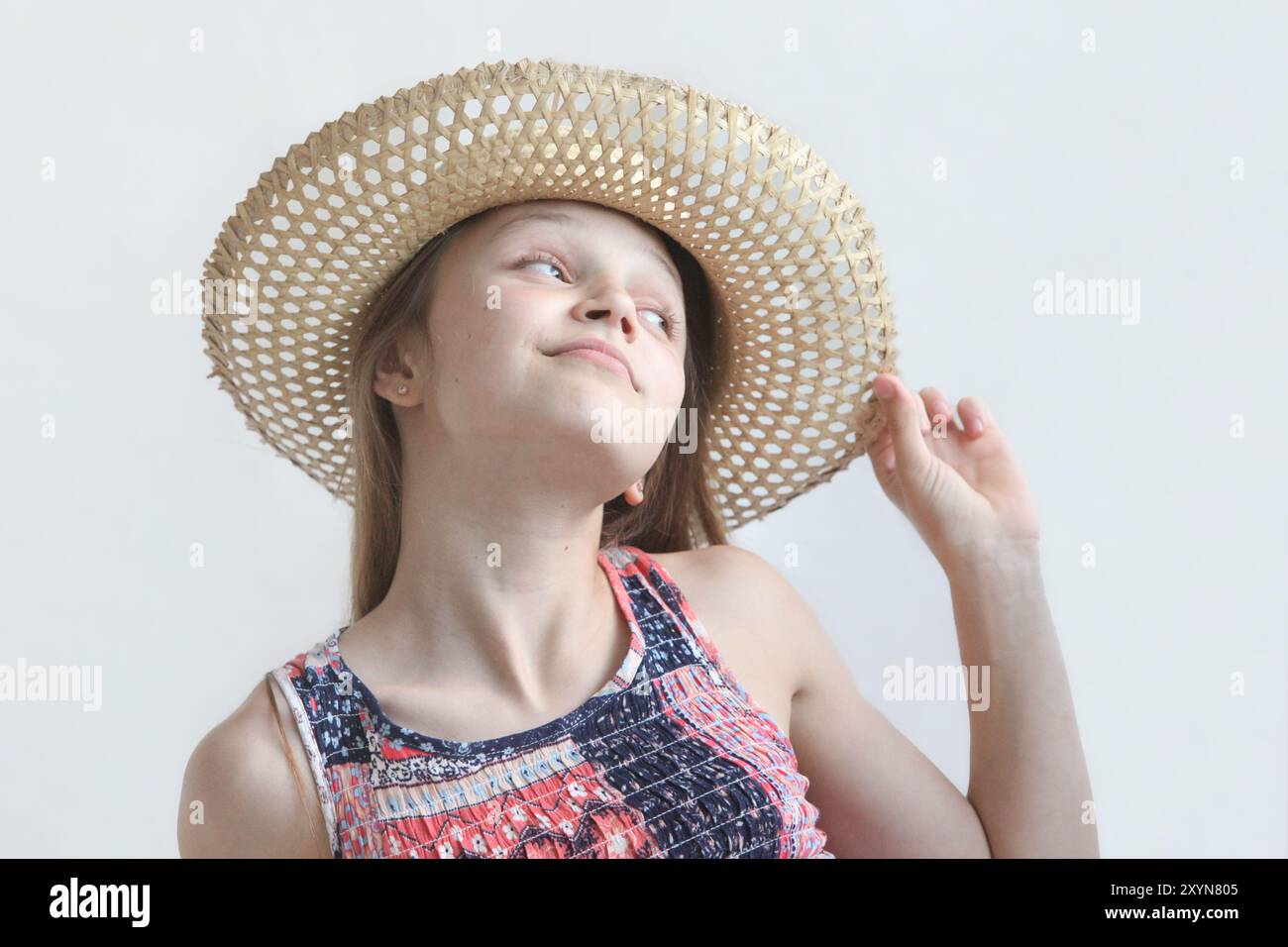 portrait of a cute little girl wearing summer dress and straw woven hat ...