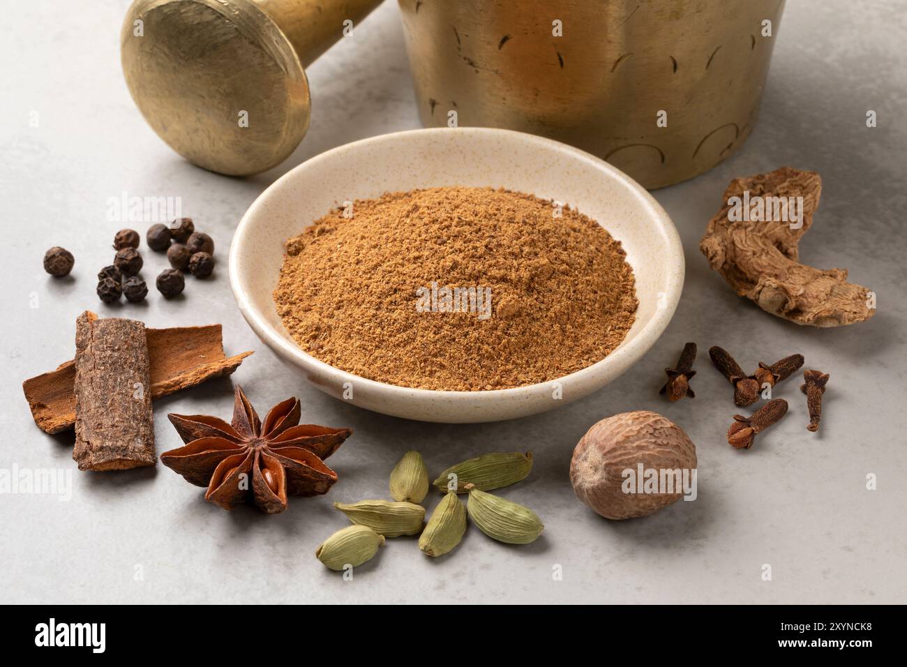 Heap of traditional ground spicy coffee herbs and dried herbs around close up and mortar and pestle in the background Stock Photo