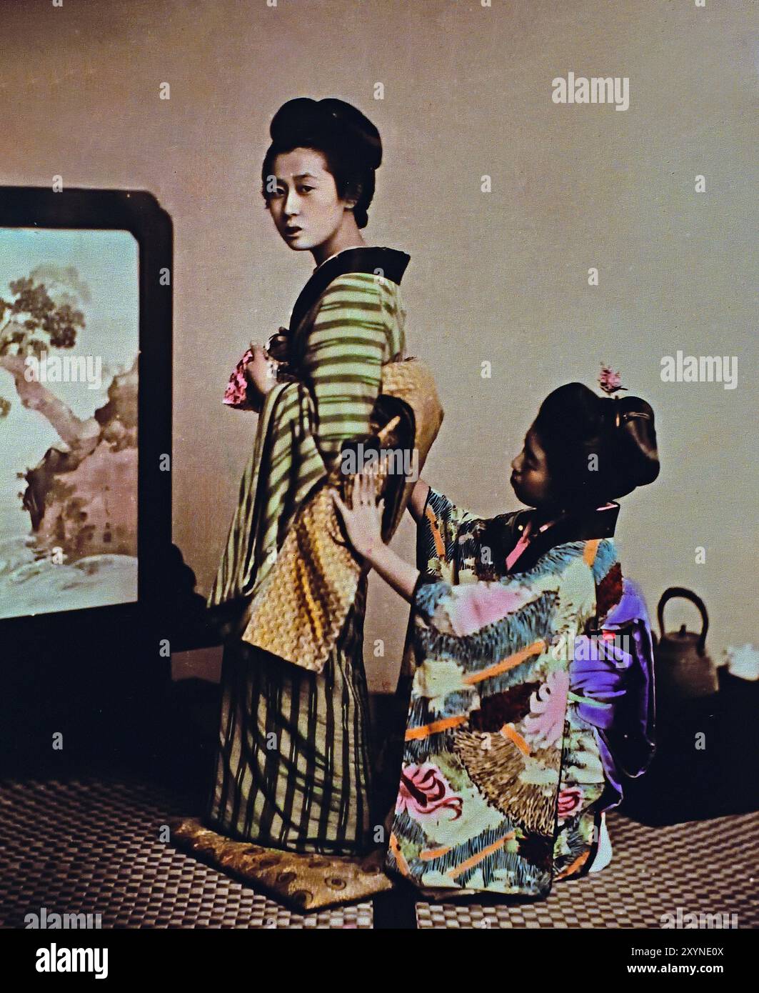 Woman being dressed 1895 By Seibei Kajima, active in the Meiji period (1868—1912). “Millionaire Photographer,” who contributed much to the world of photography in Japan.Japanese hand-coloured black and white photo Japan late 19th - beginning of 20th-century vintage albumen photograph ( Historic History ) digital improved reproduction. Stock Photo