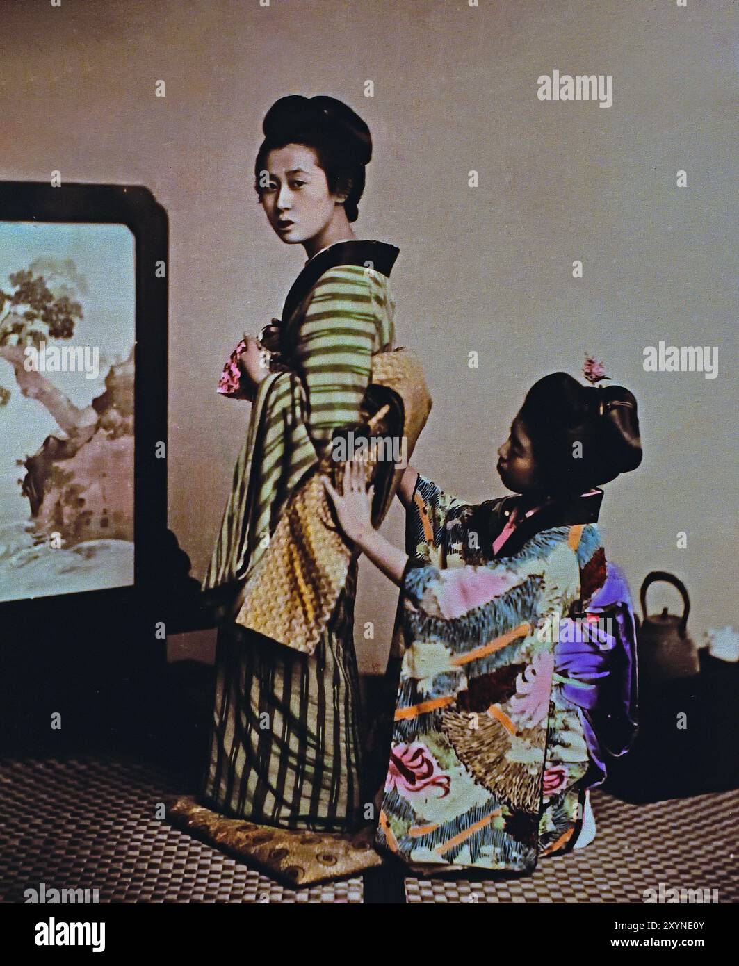 Woman being dressed 1895 By Seibei Kajima, active in the Meiji period (1868—1912). “Millionaire Photographer,” who contributed much to the world of photography in Japan.Japanese hand-coloured black and white photo Japan late 19th - beginning of 20th-century vintage albumen photograph ( Historic History ) digital improved reproduction. Stock Photo